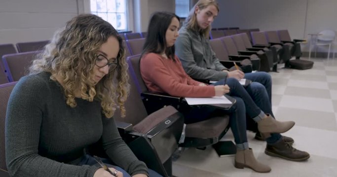 Male student cheating on a test looking at a fellow student's answers