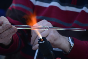 Craftsman glassblower at work. Handmade glass. Fire and glass are melting. Gas burner and flame