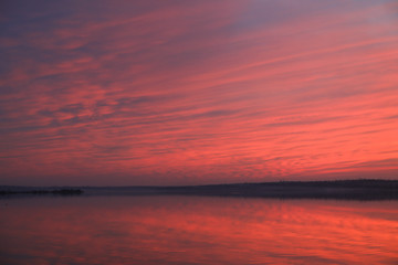 Obraz premium Dramatic sunset sky background with river, fiery clouds, yellow, orange and pink colour, nature background. Beautiful skies