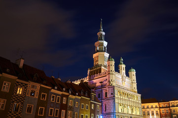 Historic tenement houses and the Renaissance town hall with a tower at night in Poznan.