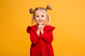 baby girl portrait isolate yellow background.Stylish little baby with hands up. Portrait of shocked little girl in red dress isolated on yellow background 