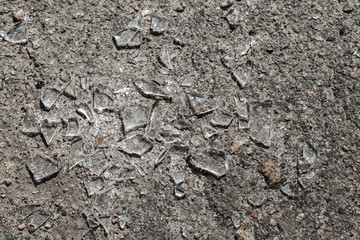 Sharp shards of car glass on the asphalt.