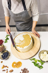 Confectioner smooths white cream on a biscuit cake with a cooking spatula. The concept of homemade pastry, cooking cakes.