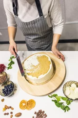Foto op Canvas Confectioner smooths white cream on a biscuit cake with a cooking spatula. The concept of homemade pastry, cooking cakes. © xartproduction