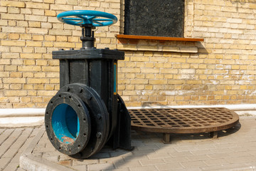 old blue valve on the black basement with brick wall in the background. control consisting of a mechanical device for controlling the flow of a fluid.