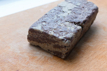 Chocolate sunflower seed Halva dessert with sesame paste and cacao on a wooden cutting board .