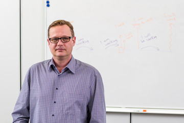 Young teacher writing english grammar on the board. Study english.