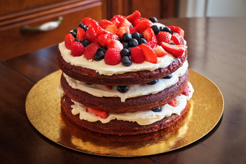 Beautiful delicious red velvet cake with strawberries and blueberries on the table