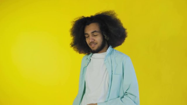 Young Afro-American man showing silence or bla bla gesture on yellow background. Concept of emotions