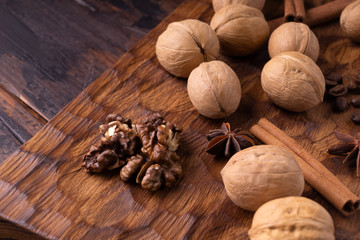 Walnuts, cinnamon, anise, and coffee beans on wooden cutting board. Nuts and spices on the table. Food composition close-up.