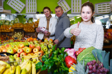Nice little girl with parents choosing fruits