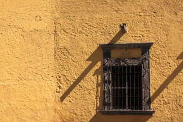 Ancient window in yellow wall with texture and shadow