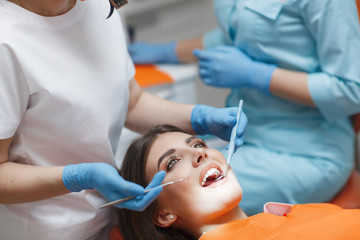 Dentist and assistant treat a patient's tooth.Doctor dentist treats teeth of a beautiful young girl patient.  Doctor dentist treats tooth.Beautiful smile. The client in the dental chair.