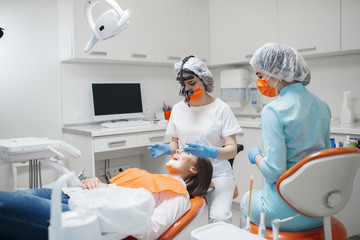 Dentist and assistant treat a patient's tooth.Doctor dentist treats teeth of a beautiful young girl patient.  Doctor dentist treats tooth.Beautiful smile. The client in the dental chair.