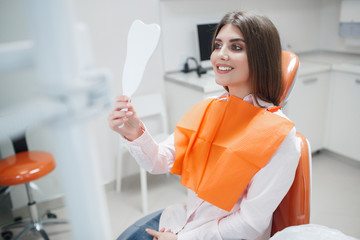 Dental clinic. Reception,examination of the patient. Teeth care. Young girl smiling, looking in the...