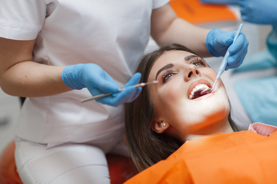 Dental clinic. Reception, examination of the patient. Teeth care. Young woman undergoes a dental examination by a dentist.Happy patient and dentist concept.Female dentist in dental office talking with