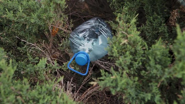 Blue big plastic bottle lying on the ground in tree in a park forest - Thrown out not recycled - Trash and pollution of the city and nature - Decayed rubbish