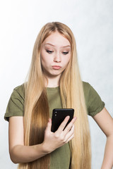 A puzzled and worried young woman holding a smartphone, looking with a surprised expression.