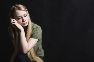 Sad young woman going to cry in a black background