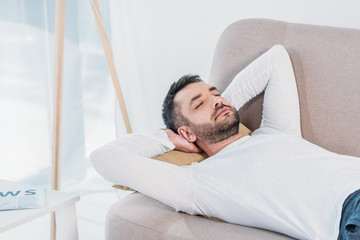 handsome bearded man with eyes closed and Hands Behind Back sleeping on couch at home