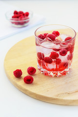 Refreshing drink with raspberries and ice. Lemonade on a white table, vertical orientation