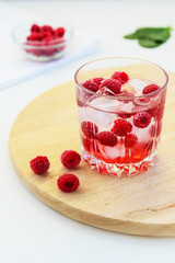 Refreshing drink with raspberries and ice. Lemonade on a white table, vertical orientation