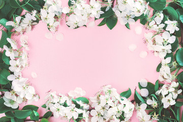 Fototapeta na wymiar Spring blooming with white flowers fruit tree branches frame on paste pink background. Flat lay with copy space, freshness concept for invitation or celebration