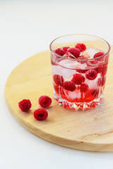 Refreshing drink with raspberries and ice. Lemonade on a white table, vertical orientation