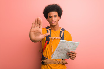 Young african american explorer man holding a map putting hand in front