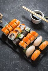 Various kinds of sushi rolls served on stone background.
