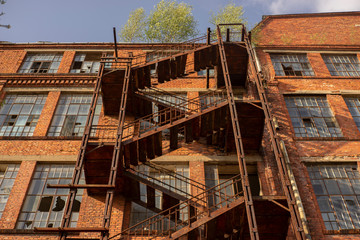 rostige, alte, verfallene Treppe an einer beschädigten Backsteinfassade