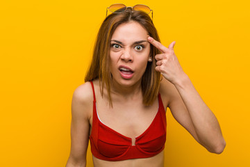 Fototapeta premium Young caucasian woman wearing bikini and sunglasses showing a disappointment gesture with forefinger.