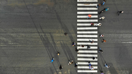 Aerial. Asphalt road with zebra pedestrian crosswalk and crowd of people. Top view.