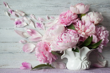 Bouquet of pink peonies in a vase on a table on a wooden background