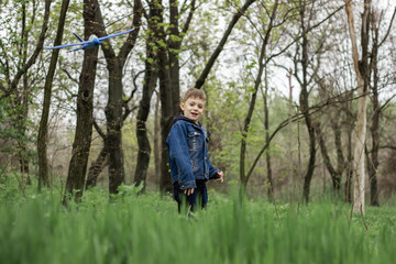 Naklejka na ściany i meble The boy launches a blue plane into the sky in a dense forest