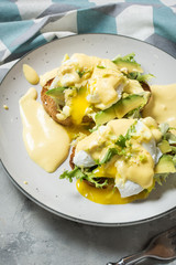 Eggs Benedict with avocado on concrete background.