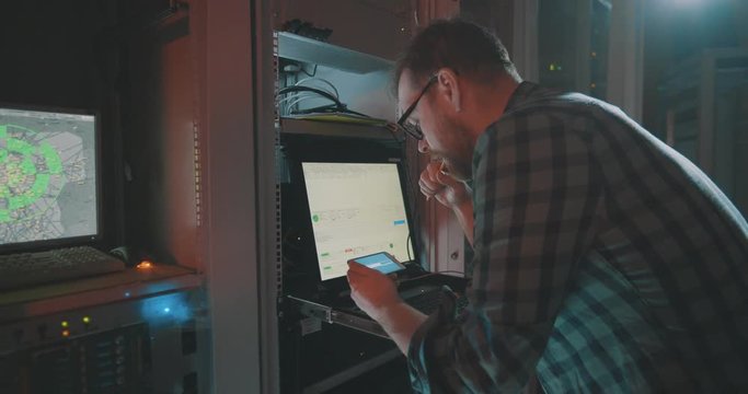 Male hacker downloading files on smartphone from laptop. Cyber security, piracy or virus concept.
