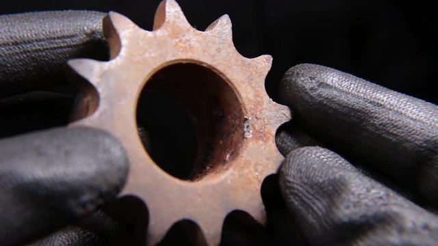 Someone holding a heavy machine part in hand wearing gloves