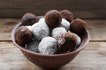 Raw vegan sweet  balls with coconut meat and cocoa powder on the wooden background.