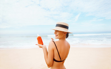 Suntan Lotion. Sexy Young Woman in Bikini  Applying Sunscreen Solar Cream.Sun Protection. Sun Cream. Skin and Body Care.Girl Holding Moisturizing Sunblock.