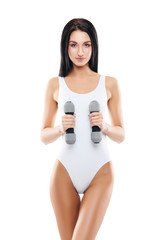 Young and fit girl pumping a dumbbells. Woman in sporty swimsuit. Sport, fitness and healthy lifestyle concept.