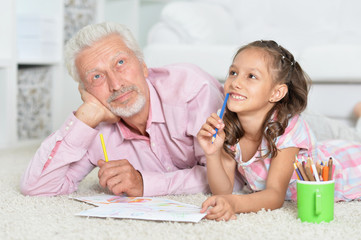 Close-up portrait of happy grandfather with granddaughter drawing together