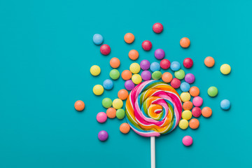 Sweet lollipop and colorful chocolate candy pills. - obrazy, fototapety, plakaty