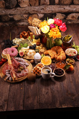 breakfast on table with bread buns, croissants, coffe and eggs