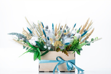 wooden box with beautiful spring floral bouquet decorated with feathers isolated on white background, close-up 