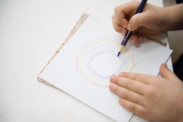 Learning materials in a montessori methodology school. Geometric materials. Little girls drawing on paper.