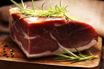 Italian prosciutto crudo or jamon with rosemary. Raw ham on wooden board