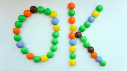 Phrase OK made of color candies on white background