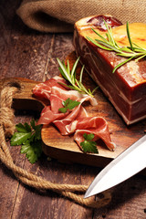 Italian prosciutto crudo or jamon with rosemary. Raw ham on wooden board