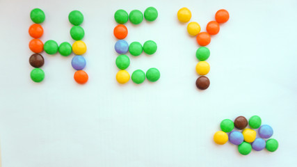 Phrase HEY made of color candies on white background